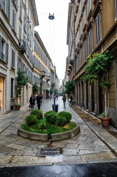 Olaszország, Milánó - Ocrober 7, 2014: Utca az ősi házak között gyalogosokkal és zöld növényekkel — Stock Fotó