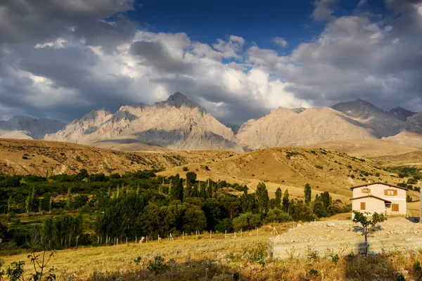 House with mountain background behind with clouds on the sky, Turkey