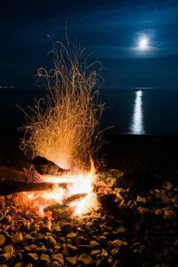 Baykal Gölü kıyısında ay yansımalı kamp ateşi.