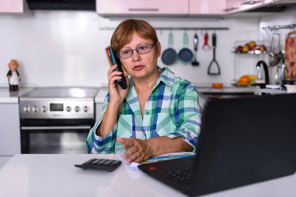 A 65-year-old woman works at home online by laptop and talks via phone because of the corona virus pandemic, more companies in are relying on the home office for their employees.