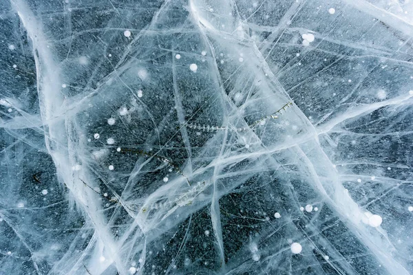 Красивый лед Байкала с абстрактными трещинами и зеленым растением в глубине — стоковое фото