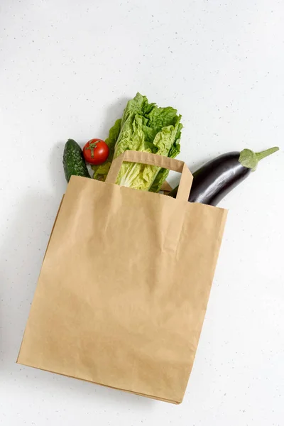 Legumes, pimentas vermelhas e verdes, berinjela, pepino, alface estão em um saco de papel em fundo isolado. Espaço de cópia da vista superior. Doação. entrega de alimentos sem contacto . — Fotografia de Stock