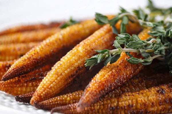 Young fried corn mini with a bundle of thyme, close-up.