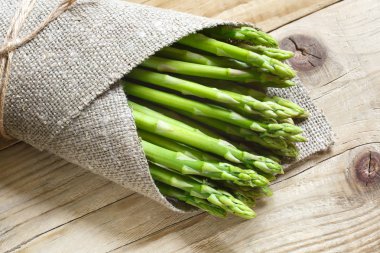 taze yeşil kuşkonmaz ahşap bir masa üzerinde bir demet. 