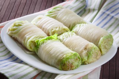 Raw cabbage rolls on a white plate.  clipart