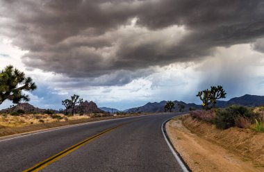 Ağır fırtına açık tehlikeli karanlık bulutların üzerinde yol, Joshua Tree National Park California ile