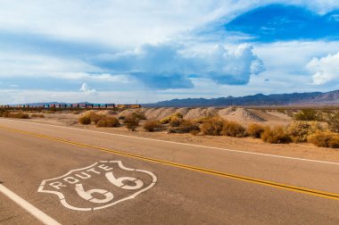 Asfalt ve arka planda uzun bir tren üzerinde işareti olan ABD Route 66 Otoban