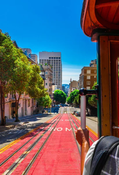 Ride with the cable car in San Francisco. The picture shows a person riding on the famous MUNI train on Powell-Mason line down the hill of Powell Street in San Francisco, California. — Stock Photo, Image