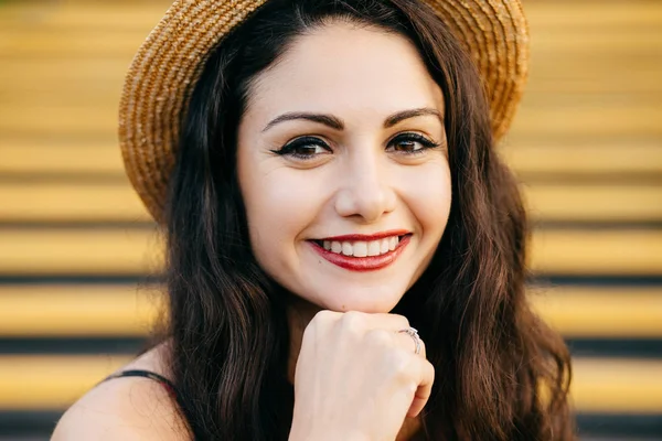 People, beauty, emotions concept. Close up portrait of beautiful brunette female with nice make-up and thin red lips smiling gently demonstrating her white teeth while keeping her hand under chin — Stock Photo, Image