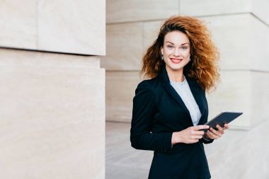 Muhteşem erkek siyah elbiseli, kıvırcık Gür saçları, mavi gözleri ve kırmızı olması hoş tablete kısa mesaj yazarken gülen dudakları boyalı. Başarılı işkadını şık giysileriyle tablet kullanma