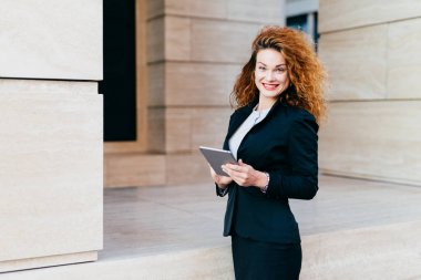 Kişi, iş, yenilik ve teknoloji kavramı. Kırmızı boyalı dudaklar, mutlu kıvırcık güzel kadın modern tablet bilgisayar, onun office builduing karşı poz holding resmi elbiseler giymiş