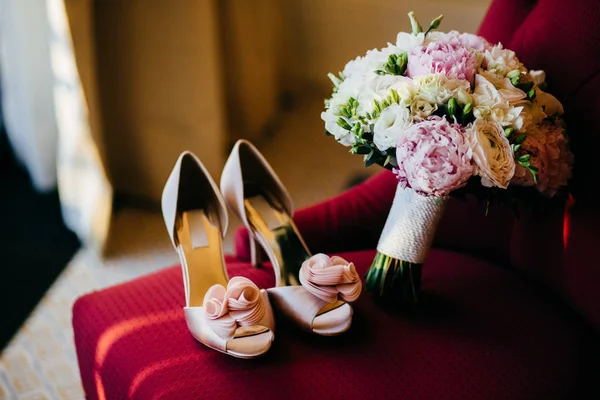 Zapatos de novia y ramo de bodas con flores suaves en la silla roja. Preparación de boda. Accesorios de boda. Zapatos de novia rosa y exuberante ramo en la habitación de la novia. La mañana de la novia. Boda foto — Foto de Stock