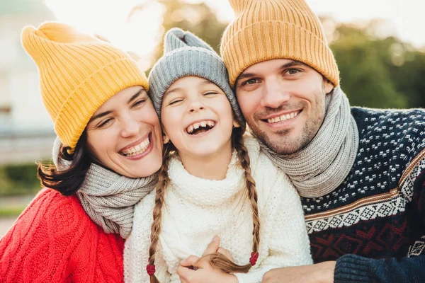 Menina feliz com tranças, veste camisola de malha quente, fica entre pai e mãe, rir feliz, ter sorrisos sinceros em seus rostos. Família relaxada ter férias, passar um bom tempo juntos — Fotografia de Stock