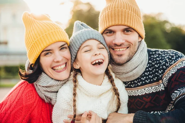 Retrato horizontal de mulher feliz sorridente e homem se divertem com sua filha, usam chapéus de malha, camisolas quentes e lenços, indo no parque para caminhar juntos. Passar tempo no círculo familiar — Fotografia de Stock