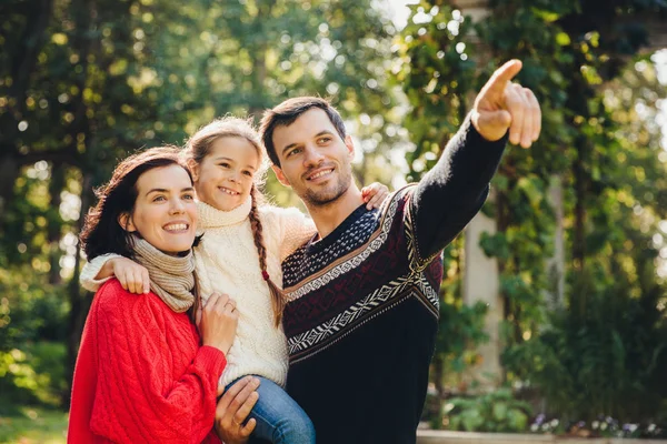 Retrato ao ar livre de família amigável feliz sorridente têm andar juntos. Pai afetuoso mostra a sua pequena filha algo à distância. Família admirar nascer do sol, bela natureza, usar roupas quentes — Fotografia de Stock