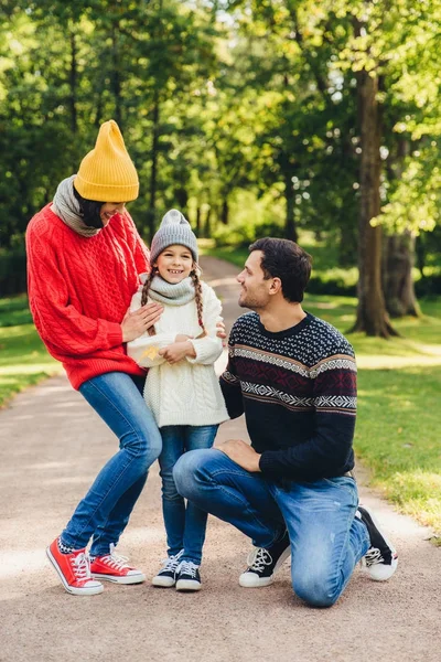 Urocze małe dziecko ładny jest obsługiwane przez rodziców, Cieszę się, że podziela jej emocje po wizycie kinder garten, ma dobry relaks w parku. Model rodzinnych spacerów w parku, szczęśliwy wyrażeń — Zdjęcie stockowe