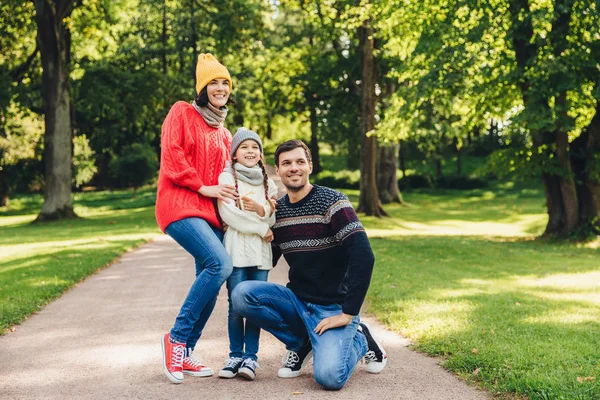 Família repousante despreocupada caminhar juntos, desfrutar do tempo ensolarado outono, parque bonito verde e ar fresco, posar na câmera, abraçar uns aos outros, ter relacionamento modelo. Criança alegre e pais — Fotografia de Stock