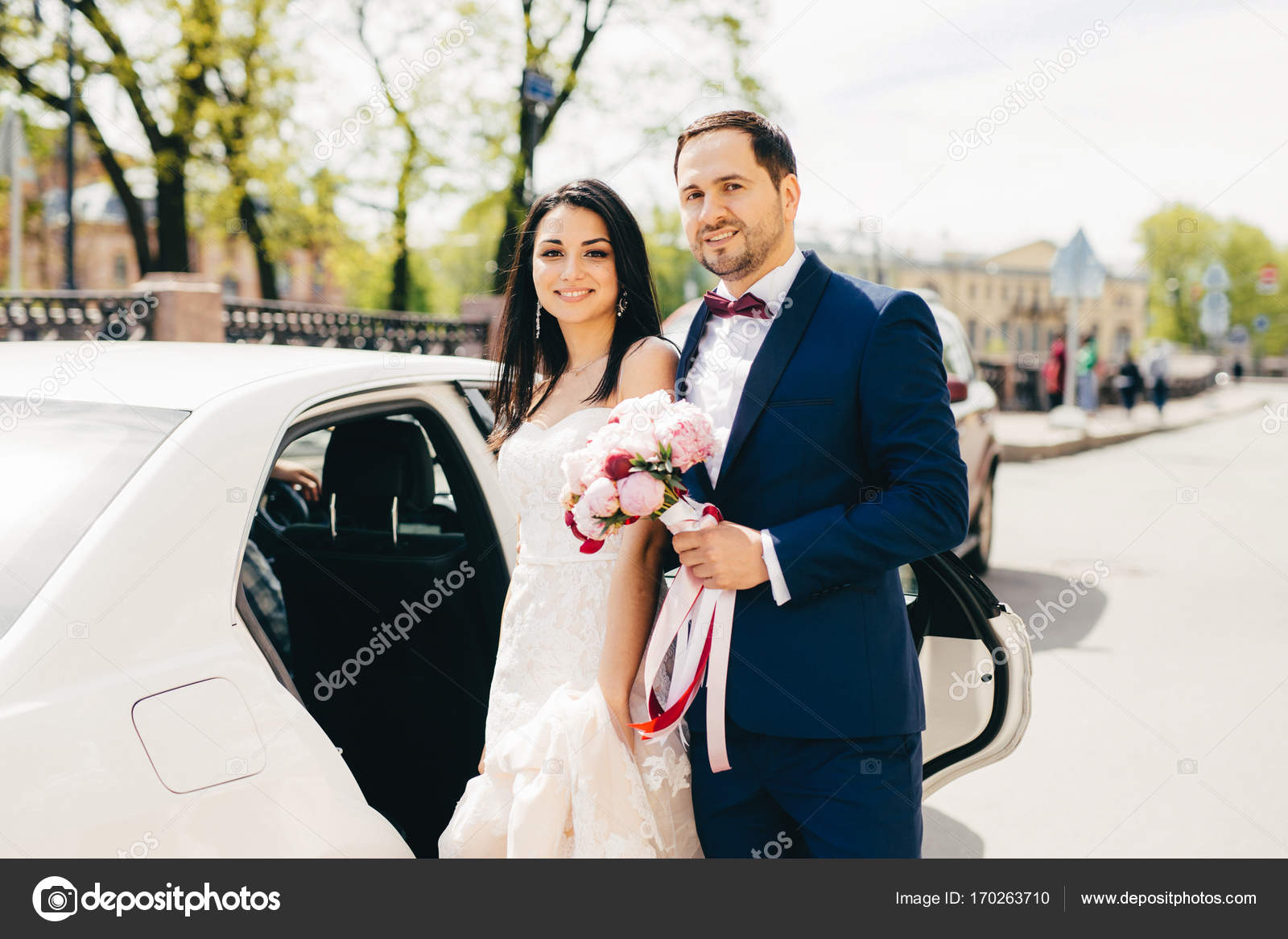 Hermosa pareja de casados se paran uno al lado del otro cerca del coche, van en Hermosa pareja de casados se paran uno al lado del otro cerca del coche, van en