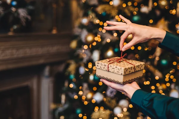 Дивовижна і приємна концепція моментів. Жінка обмотує новорічний подарунок як стоїть у вітальні біля красивої прикрашеної ялинки. Свята, x mas і концепція святкування . — стокове фото