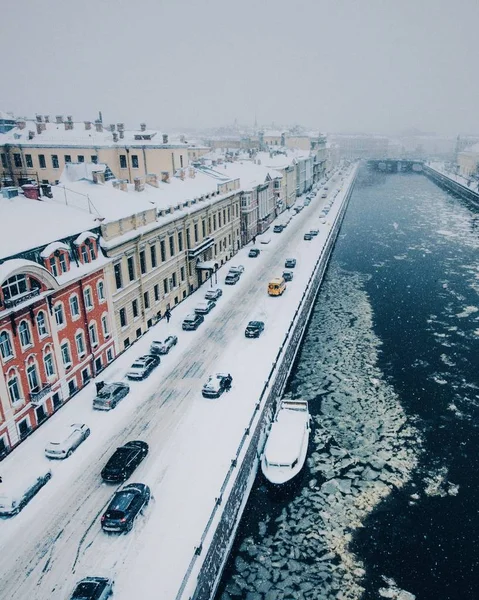 Schneebedeckter Winter in einer schönen Stadt oder Stadt. Blick von oben auf den zugefrorenen Fluss, viele Autos auf der Straße, uralte Einquartierungen. Charmante Winterzeit in der Großstadt. wunderschönes Panorama — Stockfoto
