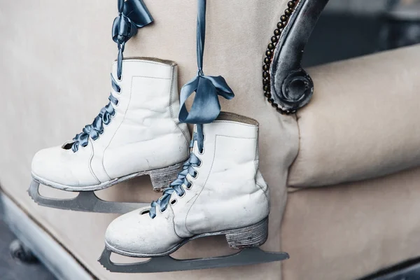Photo of pair worn winter leather white skates for figure skating with shoelaces hang on ribbon. Used women`s skates of professional skater or ice hockey player — Stock Photo, Image