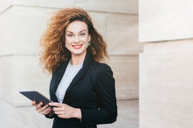 Muhteşem erkek siyah elbiseli, kıvırcık Gür saçları, mavi gözleri ve kırmızı olması hoş tablete kısa mesaj yazarken gülen dudakları boyalı. Başarılı işkadını şık giysileriyle tablet kullanma