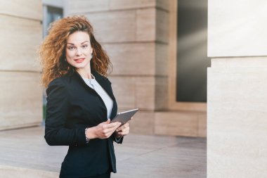 İnsanlar, iş, modern teknoloji kavramı. Güzel iş kadını siyah ceket ve onun ofisinin modern tablet ile ayakta, iş stratejisi geliştirme, kameraya bakarak etek giyiyor