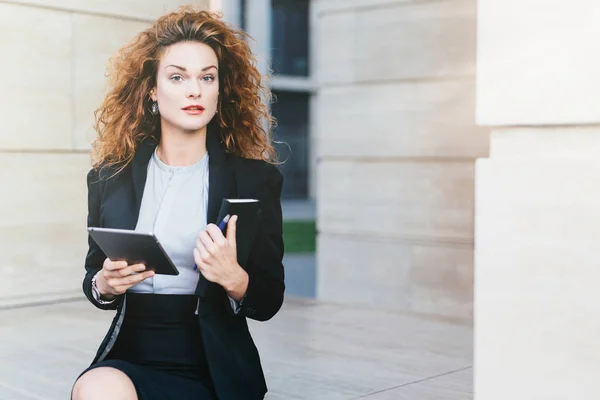 Horizontal portrait of pretty confident businesswoman dressed formally, holding her pocket book with pen and tablet computer, being busy with her work. People, lifestyle, career, business concept — Stock Photo, Image