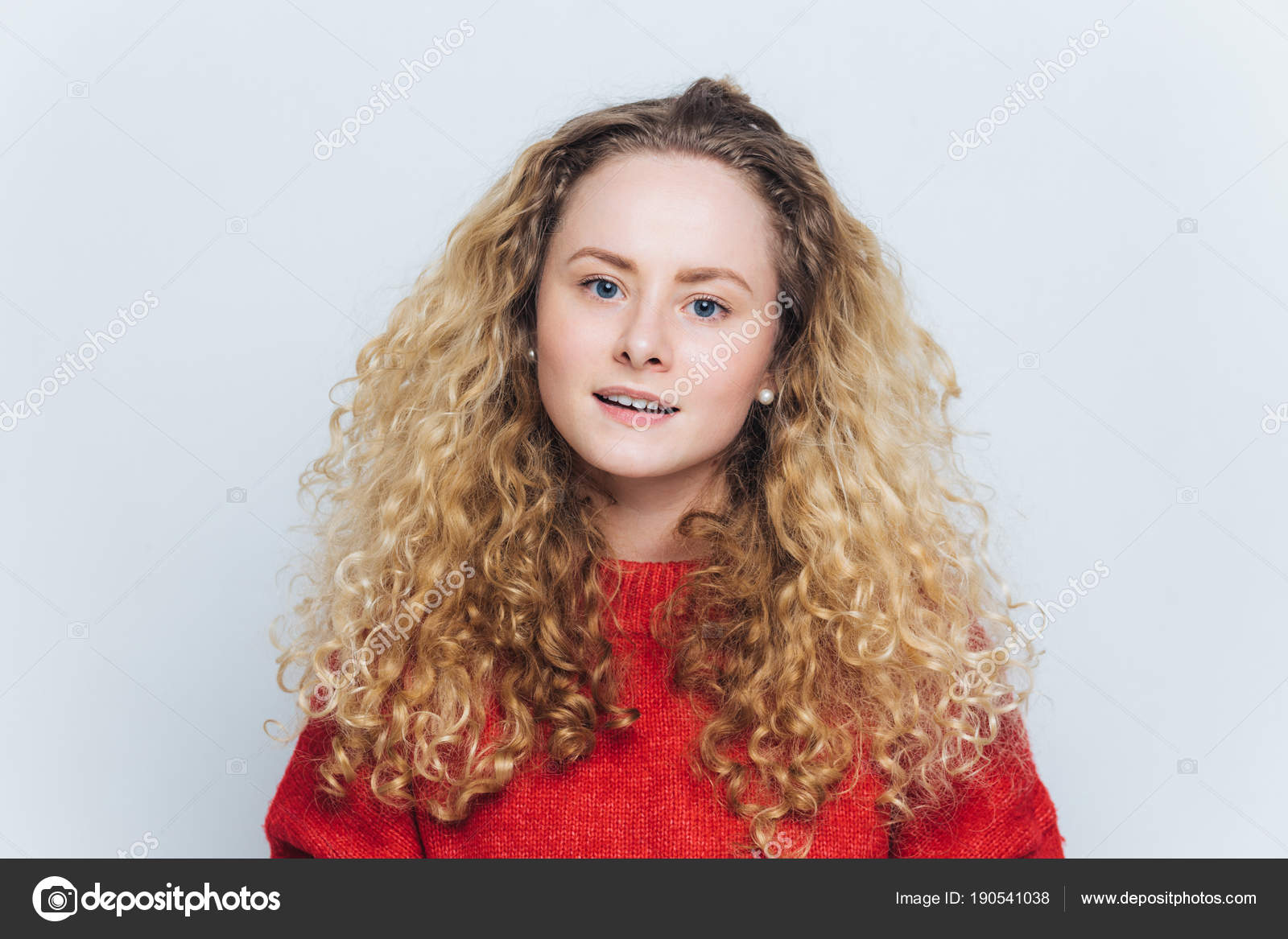 Satisfied Adorable Blue Eyed Female With Curly Light Hair Wears Red Sweater Has Curious Expression Isolated Over White Background Attractive Woman Has Blonde Hair Poses In Studio Alone Stock Photo C