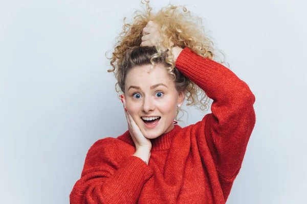 Retrato de sorprendida chica feliz sorprendido con cola de caballo rizado, mira fijamente a la cámara, mantiene la boca ampliamente abierta, se pregunta su gran éxito, modelos contra fondo de estudio blanco. Concepto de emoción — Foto de Stock