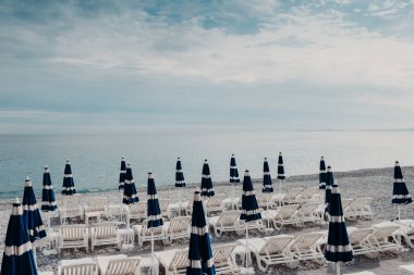 Mavi Bulutsuz gökyüzü, güzel deniz manzarası sakin engin deniz ya da okyanus ve kumlu plaj şezlong ve yaz şemsiye, eğlence için. Sıcak yer mükemmel yaz resort için