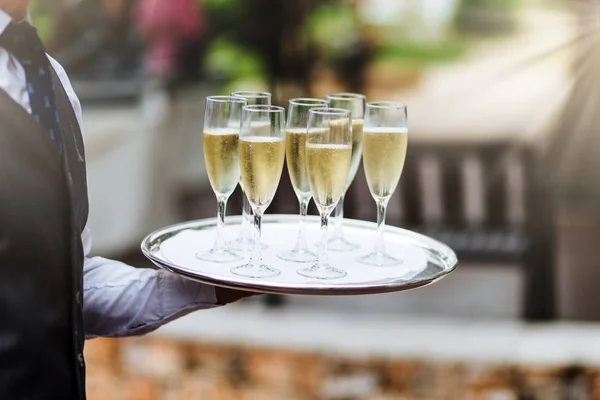 Oigenkännlig servitör i formella kläder håller bricka med glas champagne, bär drycker på festbordet gäster, levererar bra service för besökare. Gästfrihet, service och dricka koncept — Stockfoto