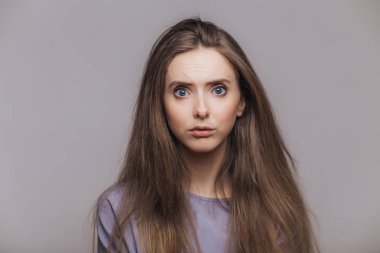 Stüdyo çekim hoş duyar gibi ifade şaşkın karanlık uzun saçlı, mavi gözlü kadın modeli arıyorum muhatap, gri arka plan üzerinde izole haberleri şok edici. Yüz ifadeleri kavramı
