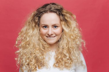 Güzel genç kadın, çok mutlu bak, alt dudağını ısırıp, kameraya mutlu görünüyor, hafif dalgalı saç ve mavi gözleri vardır, yalnız karşı pembe bir arka plan teşkil etmektedir. İnsanlar, güzellik ve positiveness kavramı