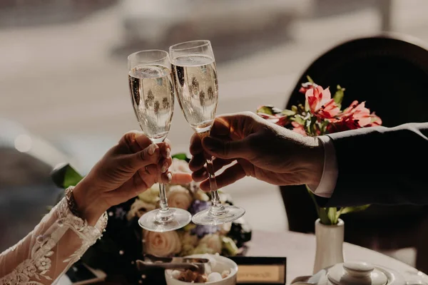 Casal romântico jantar juntos no café ou restaurante, copos de champanhe clink, belos buquês no fundo. Pessoas, celebração e feriados conceito — Fotografia de Stock