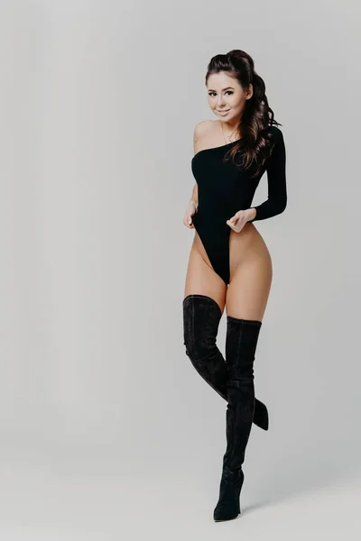 Εσωτερική λήψη ελκυστικής γυναίκας με σέξι μαύρα ρούχα, δείχνει όμορφο λεπτό σώμα, ποζάρει για το εξώφυλλο του περιοδικού μόδας, απομονωμένη σε γκρι φόντο. Τέλεια σέξι φιγούρα. Ζεστές γυναικείες στάσεις εσωτερική — Φωτογραφία Αρχείου