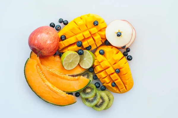 Berbagai macam buah tropial juicy pada latar belakang putih. Potongan pada melon, mangga oranye, kiwi, kapur, blueberry dan apel. Hidangan vegetarian . — Stok Foto