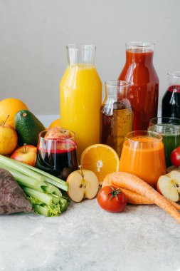 Sağlıklı sebze ve meyve suları veya cam şişelerde smoothie, portakal olgun dilimleri, elma, kırmızı domates, havuç, kereviz, avokado beyaz arka plan izole.