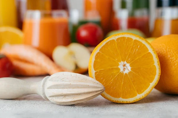 Laranja fresca fatiada com espremedor. Fazendo suco de frutas frescas. Cor laranja. Frascos de sumo desfocados no fundo. Tiro horizontal — Fotografia de Stock