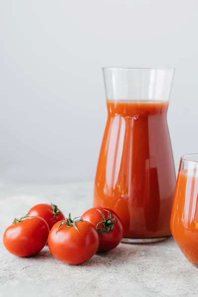 Isolerad vertikal bild av nygjord tomatjuice, mogna tomater med gröna blad på vit bakgrund. Grönsaker fulla av vitaminer. — Stockfoto