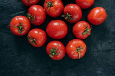 Koyu arka planda yeşil yaprakları ile taze hasat kırmızı domates. Organik doğal sağlıklı gıda. Sulu çiğ domates. Taze sebzeler