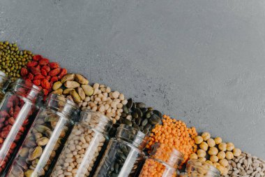 Zero waste. Organic grains in glass jars. Pumpkin seeds, chickpea, mung beans, lentils, goji berry, pistachio, sun seeds spilled from bottles. Copy space at upper right corner