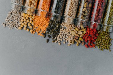 Healthy products in glass jars. Organic grains in containers on grey background. Blank space at bottom for your promotional text. Vegetarian food
