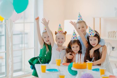 Çocuklar parti ve kutlama konsepti. Bir grup küçük çocuk arkadaş fotoğraf çeker, kollarını kaldırır ve mutlu bir şekilde gülümser, doğum günü partisi verir, şenlik düzenler, aptalca şeyler yaparlar.
