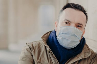 Hasta adam bulaşıcı hastalıklara karşı koruyucu maske takıyor, düşünceli bir ifadesi var, tehlikeli salgın durumunda güvende olmaya çalışıyor, dışarıda duruyor. Virüs önleme yayıldı. Coronavirüs.