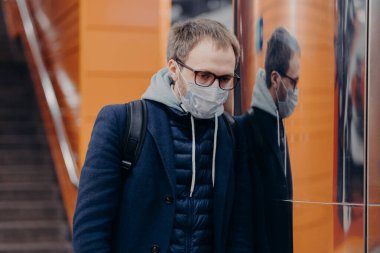 Hastalıklı adam koronavirüse karşı koruyucu maske takıyor metro ya da metroda poz veriyor kendini bulaşıcı hastalıklardan koruyor, sırt çantası taşıyor. Avrupa 'da Covid-19 sırasında toplu taşıma