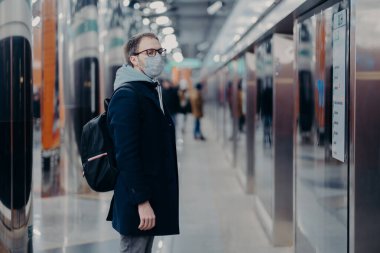İnsan yolcunun metro istasyonunda pozu, koronavirüs zamanında tıbbi maske takması, treni beklemesi, toplu taşıma araçlarıyla işe gitmesi. Virüs, hastalık ve grip konsepti