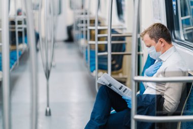 Hasta adamın nefes almakta zorlanıyor, elini göğsünde tutuyor, metroyla seyahat ediyor, tıbbi maske takıyor ve lastik eldiven takıyor. Koronavirüs salgını. Karantina nedeniyle yolcu trafiğinde ciddi düşüş
