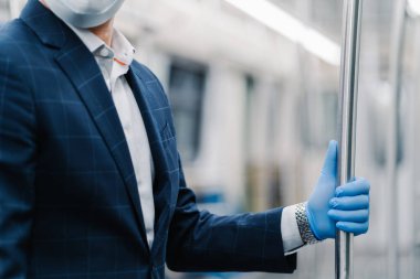 İnsan yolcu Coronavirus 'tan koruyucu eldiven giyer metro vagonundaki tırabzanlara dokunur, toplu taşıma aracında poz verir, resmi olarak giyinir. Virüs, grip, karantina ve sağlık konsepti