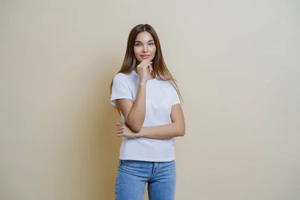 Foto Morena Joven Europea Sostiene Barbilla Lleva Camiseta Blanca Jeans —  Fotos de Stock